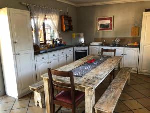 eine Küche mit einem großen Holztisch und Stühlen in der Unterkunft Natures Rest Lapa in Oudtshoorn
