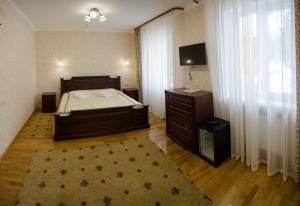 a bedroom with a bed and a dresser and a television at Naftusya Hotel in Truskavets