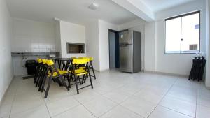 a kitchen with yellow chairs and a table and a refrigerator at Loft torres Las piedras praia da Cal in Torres +11 photos