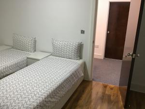 une chambre avec deux lits et une porte donnant sur un couloir dans l'établissement Residential Quarters, General Gordon Square, à Londres