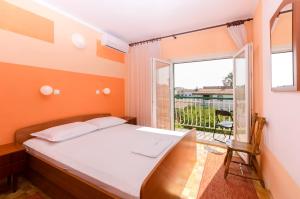 a bedroom with a bed and a large window at Rooms Dejana in Vodice