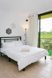 a large white bed in a bedroom with a balcony at Langkawi Green View Cottage in Pantai Cenang