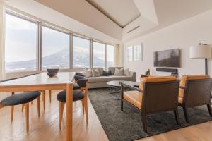 a living room filled with furniture and a large window at Skye Niseko in Niseko