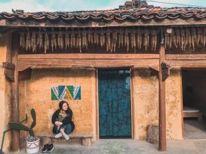 a woman sitting on a bench in front of a building at Homie homestay in Loung Co