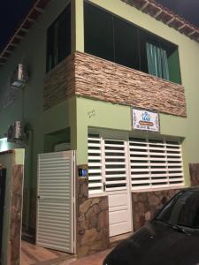 una casa con puertas blancas y un coche aparcado fuera en O Mar Hospedagem - SUÍTES PRIVADAS, en Arraial do Cabo