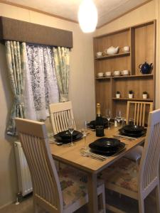 uma mesa de jantar com 2 cadeiras e uma mesa com copos em Seaside Cove Static Holiday Home With Private Hot Tub em Mablethorpe