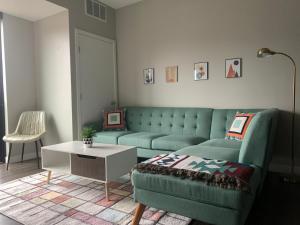 salon z zieloną kanapą i stołem w obiekcie Sleepover Premier Downtown Des Moines Apartments w mieście Des Moines