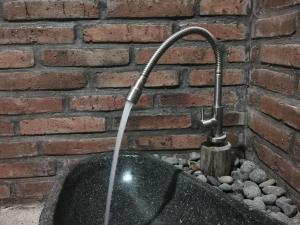a water fountain in front of a brick wall at Coconut Tree Cottages in Batukaras