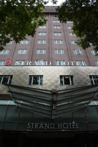 um sinal na frente de um grande hotel em Strand Hotel em Singapura