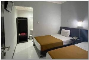 GabungにあるLosmen Family Syariah Bypass Juanda Mitra RedDoorzの小さな部屋で、ベッド2台、鏡が備わります。