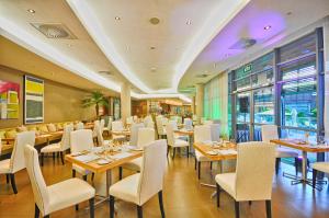 Holiday Inn Mauritius Mon Trésor, an IHG Hotel في بلو باي: مطعم بطاولات خشبية وكراسي بيضاء