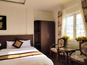 New Hampton Suits-Tam Xuan Centre Hotel في دالات: غرفة نوم بسرير وكرسي ونافذة
