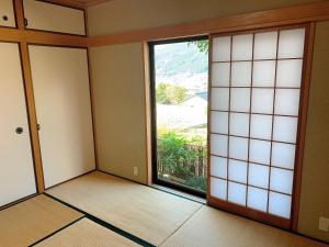 um quarto vazio com uma grande janela e uma porta em Yufuin Sunday em Yufu