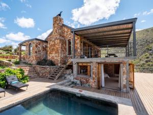 uma casa de pedra com uma piscina em frente em Die Beloofde Land em Uniondale