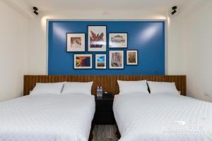 two beds in a bedroom with a blue wall at 巷弄民宿 Alleyway in Taitung City