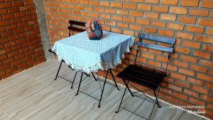 Aum Hum Homestay في فانغ: طاولة وكرسيين بجانب جدار من الطوب