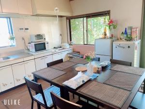 eine Küche mit einem Tisch mit Stühlen und einem Kühlschrank in der Unterkunft Yufuin Sunday in Yufu