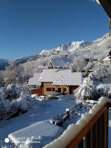 una casa ricoperta di neve con montagne sullo sfondo di Chez Bear a Briançon