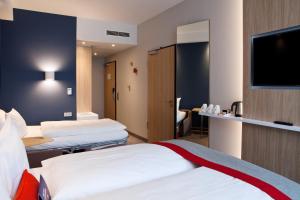 a hotel room with three beds and a flat screen tv at Holiday Inn Express - Kaiserslautern by IHG in Kaiserslautern