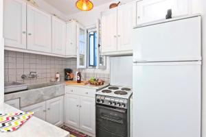 a kitchen with white cabinets and a refrigerator at Sifnos Residence in Platis Gialos