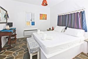 a white bedroom with a bed and a desk at Sifnos Residence in Platis Gialos