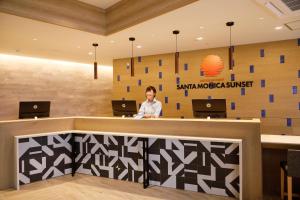 a woman standing at a reception desk in a lobby at Hot Cross Point Santa Monica in Miyako Island