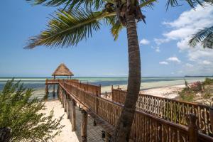 een houten pad naar het strand met een palmboom bij Kena Beach Villas in Marumbi