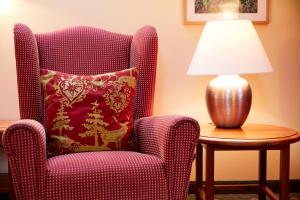 Hotel & Restaurant Stern في غموند: كرسي مع وسادة ومصباح على طاولة