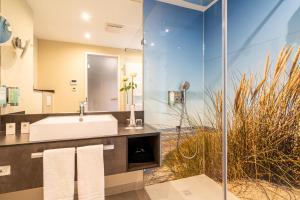 ein Bad mit einem Waschbecken und einem Spiegel in der Unterkunft ambassador hotel & spa in Sankt Peter-Ording