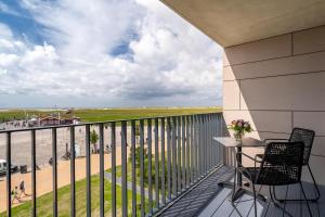 balcón con mesa y sillas y vistas a la playa en ambassador hotel & spa, en Sankt Peter-Ording