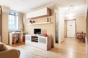 sala de estar con cocina blanca con mesa y TV en Nel cuore del Centro Storico Cozy Apartment, en Bolonia