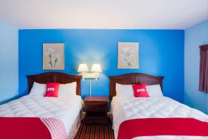 2 camas en una habitación con paredes azules y almohadas rojas en OYO Hotel Salem-Roanoke I-81, en Salem