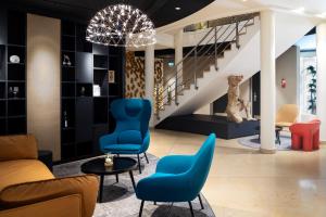 a lobby with blue chairs and a staircase at Le Richebourg Hôtel, Restaurant & Spa in Vosne-Romanée