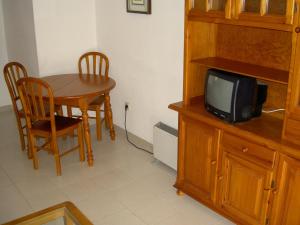 a small television sitting on top of a wooden cabinet next to a table at APCOSTAS - Hawaii Sun in La Manga del Mar Menor