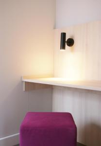 a purple ottoman in a room with a shelf at Taste Hotel Hockenheim in Hockenheim