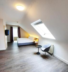 Großes Zimmer mit einem Bett und einem Dachfenster. in der Unterkunft Taste Hotel Hockenheim in Hockenheim