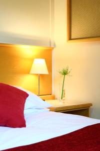 セント・アンドルーズにあるアグネス ブラッカダー ホール キャンパス アコモデーションのベッドルーム1室(赤い枕とランプ付きのベッド1台付)