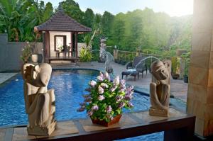 a pool with statues on a table in a yard at Hotel Puri Nusa Indah in Denpasar