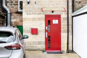 a red door on a brick building with a car parked in front at Granville Apartments in Harrogate