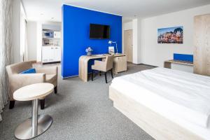 ein Schlafzimmer mit einer blauen Wand, einem Bett und einem Schreibtisch in der Unterkunft Hotel Global Inn in Wolfsburg + 50 Fotos
