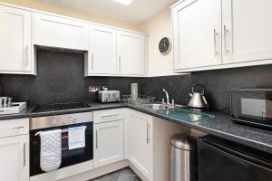 a kitchen with white cabinets and a sink at Granville Apartments in Harrogate