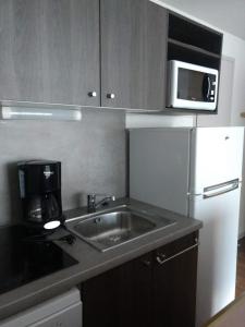 a kitchen with a sink and a white refrigerator at VVF Val-Cenis Haute-Maurienne in Lanslevillard