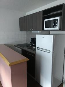 uma cozinha com um frigorífico branco e um micro-ondas em VVF Val-Cenis Haute-Maurienne em Lanslevillard