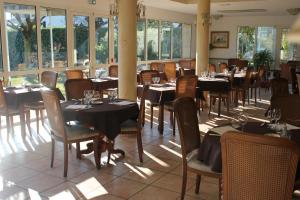 un comedor con mesas, sillas y ventanas en Logis Hôtel Les Cimes, en Argelès-Gazost