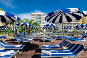 un gruppo di sedie a sdraio e ombrelloni in spiaggia di Hotel Palace a Bibione
