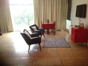 a living room with chairs and a table and a television at Pousada Beira Rio in Itumbiara