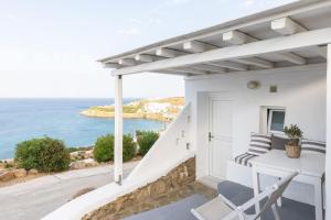 a white house with a balcony with a view of the ocean at Sea Wind Apartments in Agios Stefanos