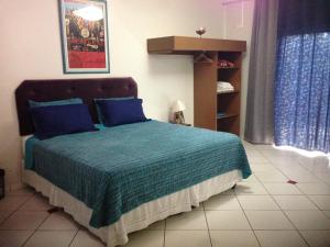 a bedroom with a bed with blue pillows at Pousada Beira Rio in Itumbiara