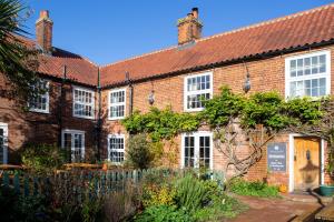 uma antiga casa de tijolos com um jardim em frente em Sutton Staithe Hotel em Sutton