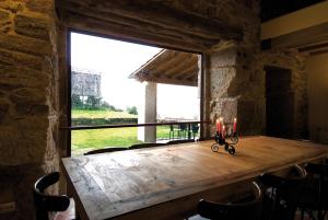 a wooden table in a room with a large window at Casa Entre-Palheiros e Casa do Canastro in Montalegre